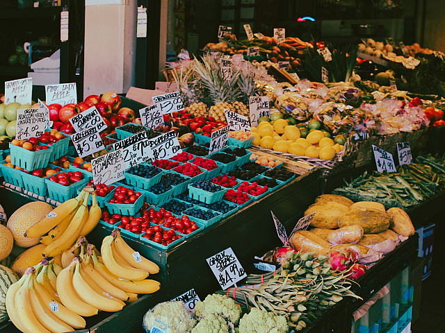 Vibrant market stall displaying a colorful variety of fresh fruits and vegetables, including bananas, berries, lemons, and leafy greens.