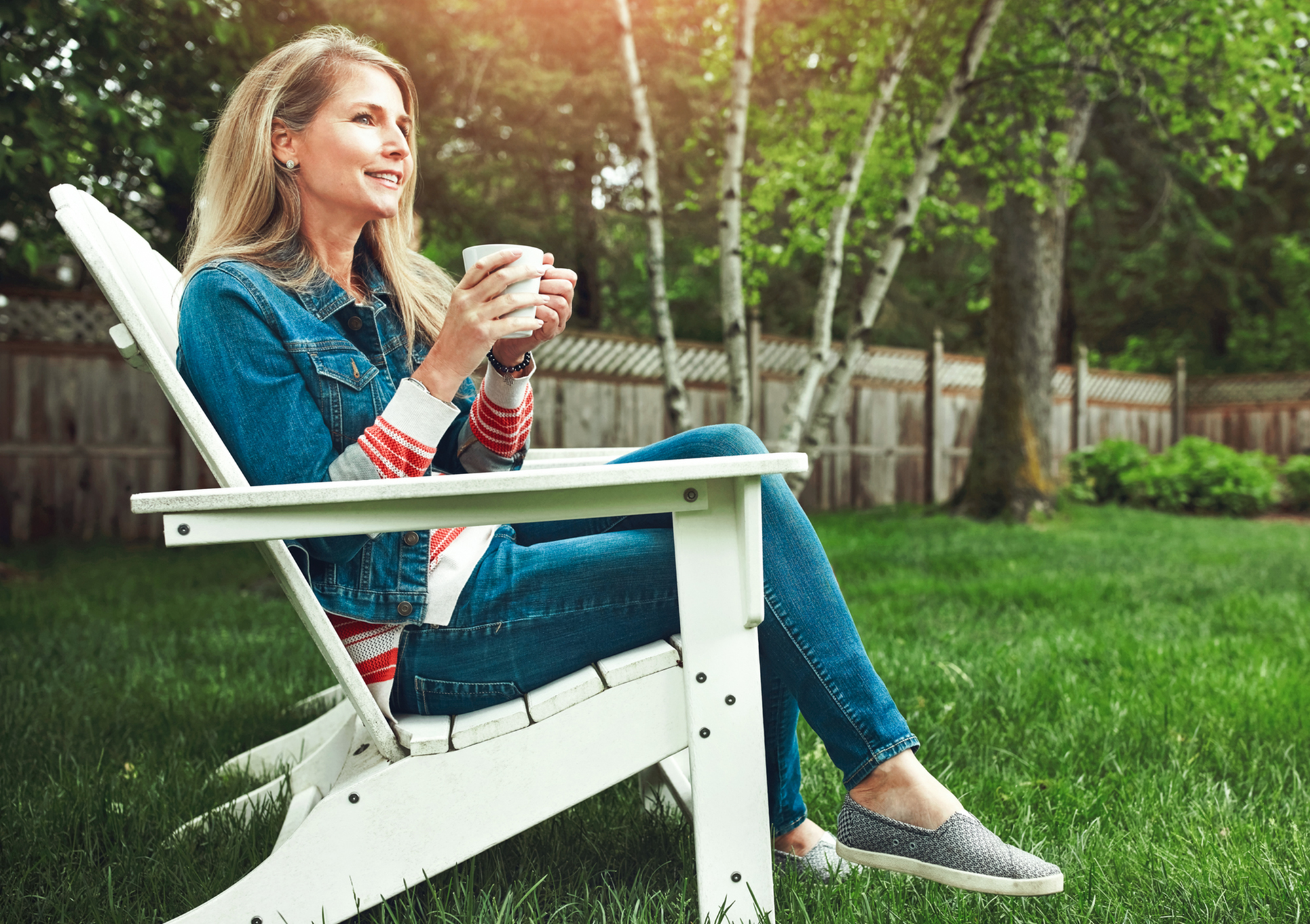 woman drinking coffee in a fenced in back yard