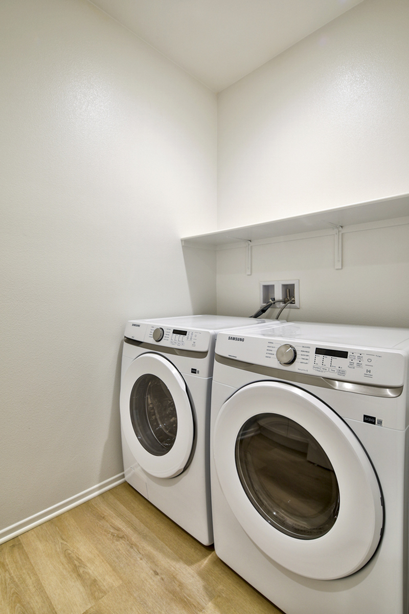 Modern laundry room with energy-efficient washer and dryer, featuring sleek design and ample shelving.