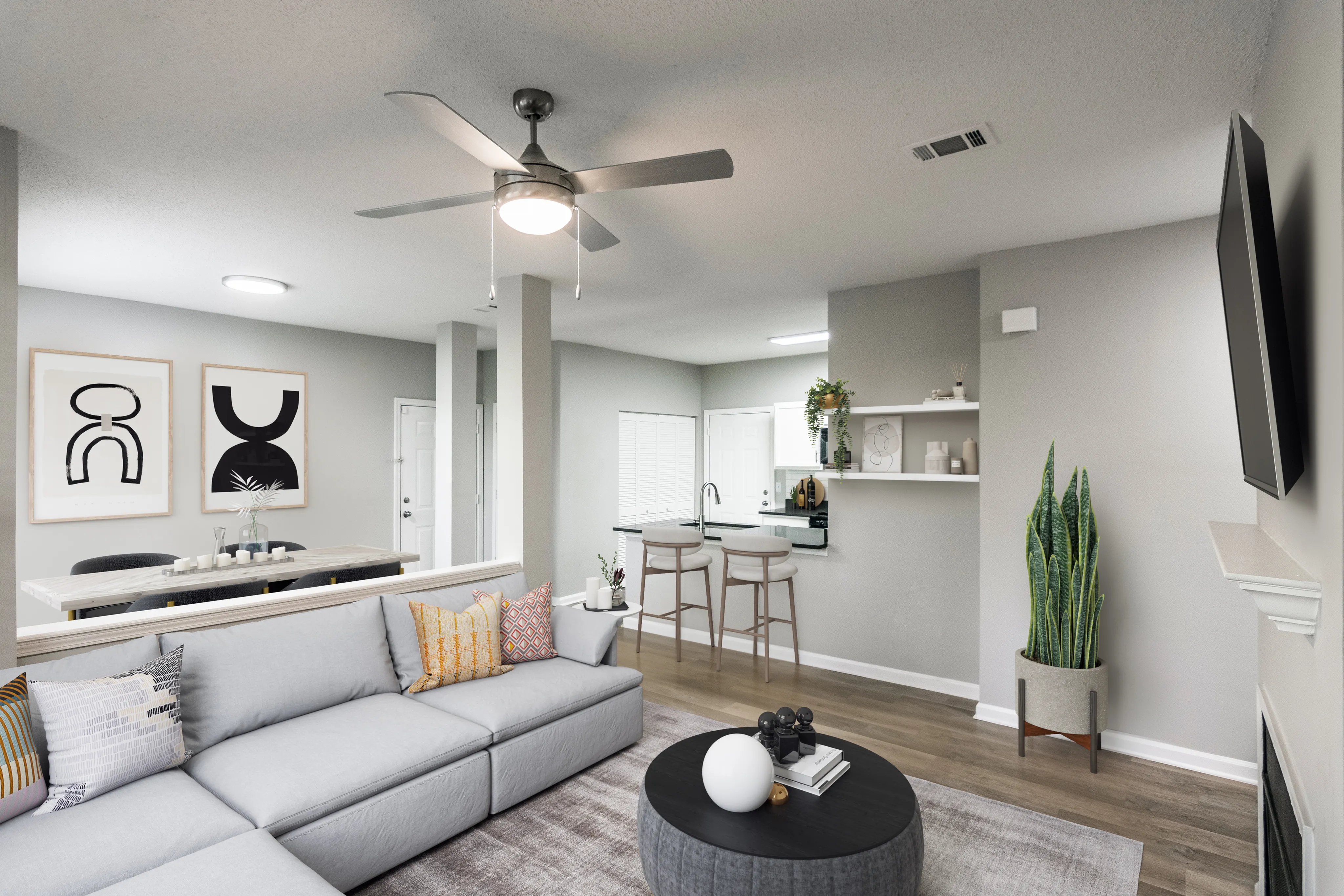 Modern living area with a stylish gray sofa, chic wall art, and a sleek kitchen with bar seating, perfect for entertaining.