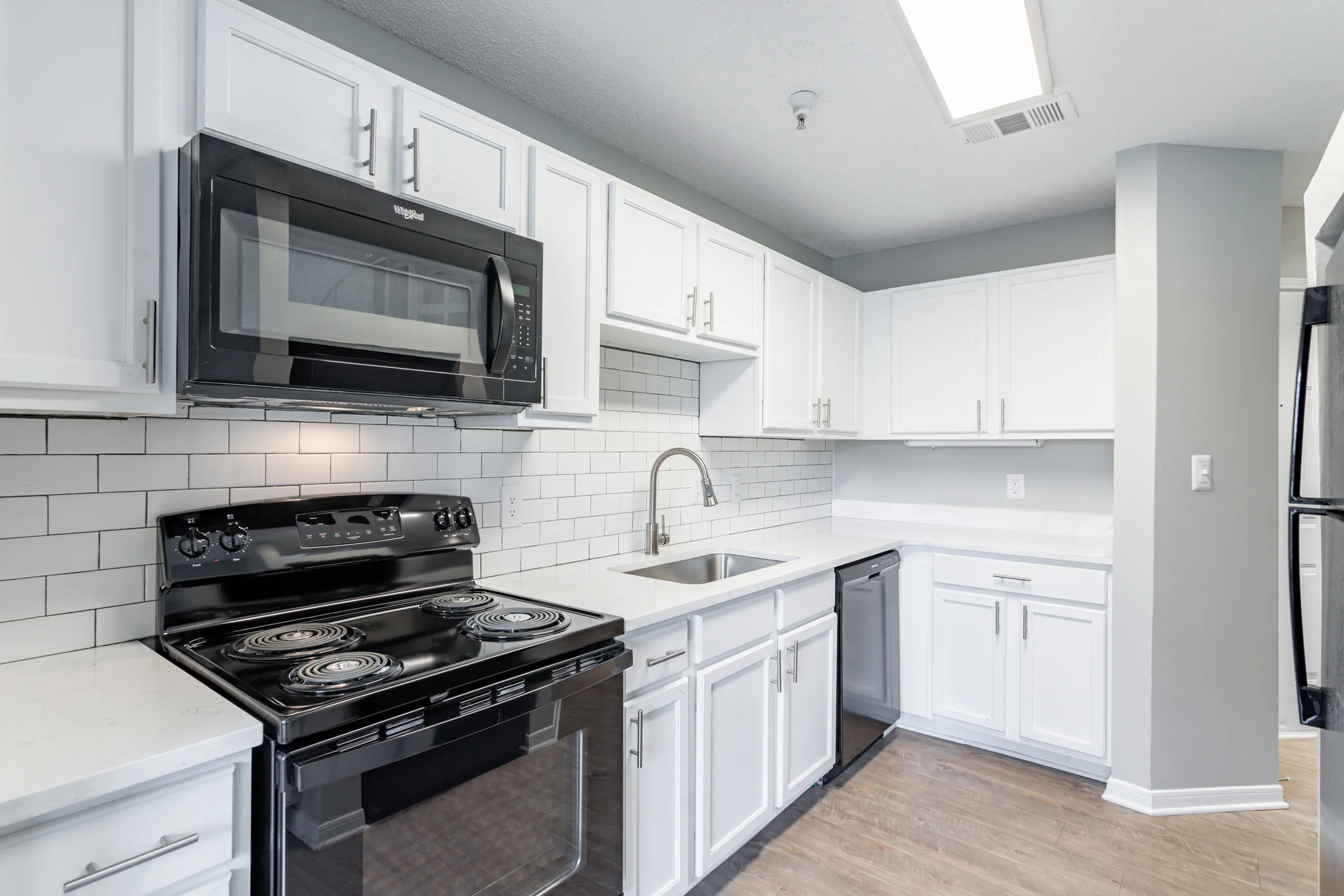 Contemporary kitchen design featuring sleek white cabinetry, a modern black stove and microwave, complemented by a chic subway tile backsplash.