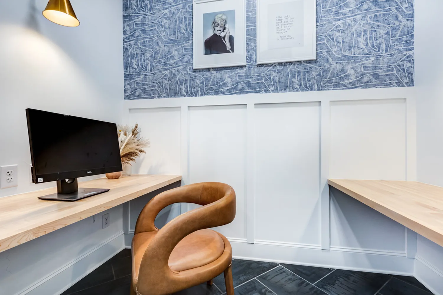 Cozy home office with stylish wood desk, elegant tan chair, and modern decor accentuating a blue textured wall.