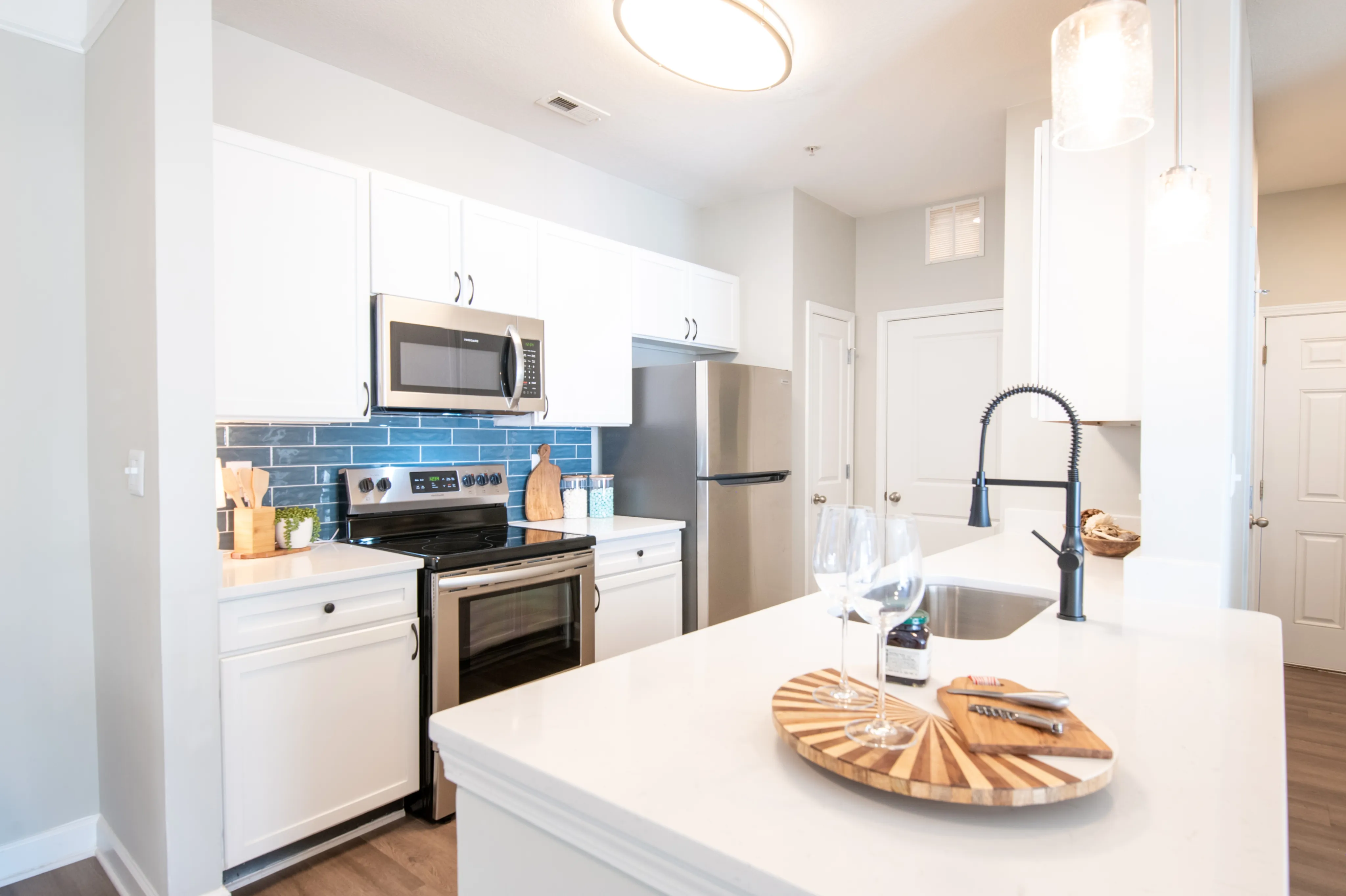 Modern kitchen with sleek stainless steel appliances, elegant white cabinetry, and chic blue tile backsplash, perfect for culinary enthusiasts.