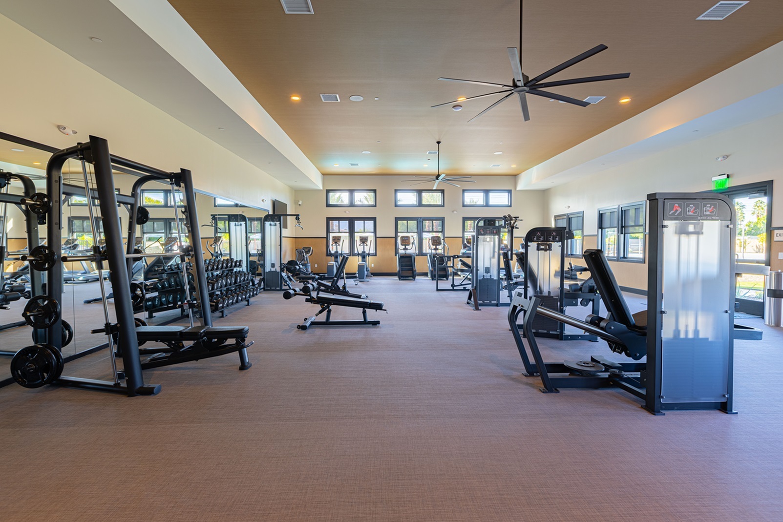 Spacious modern gym with state-of-the-art equipment, large windows, and sleek design for an invigorating workout experience.