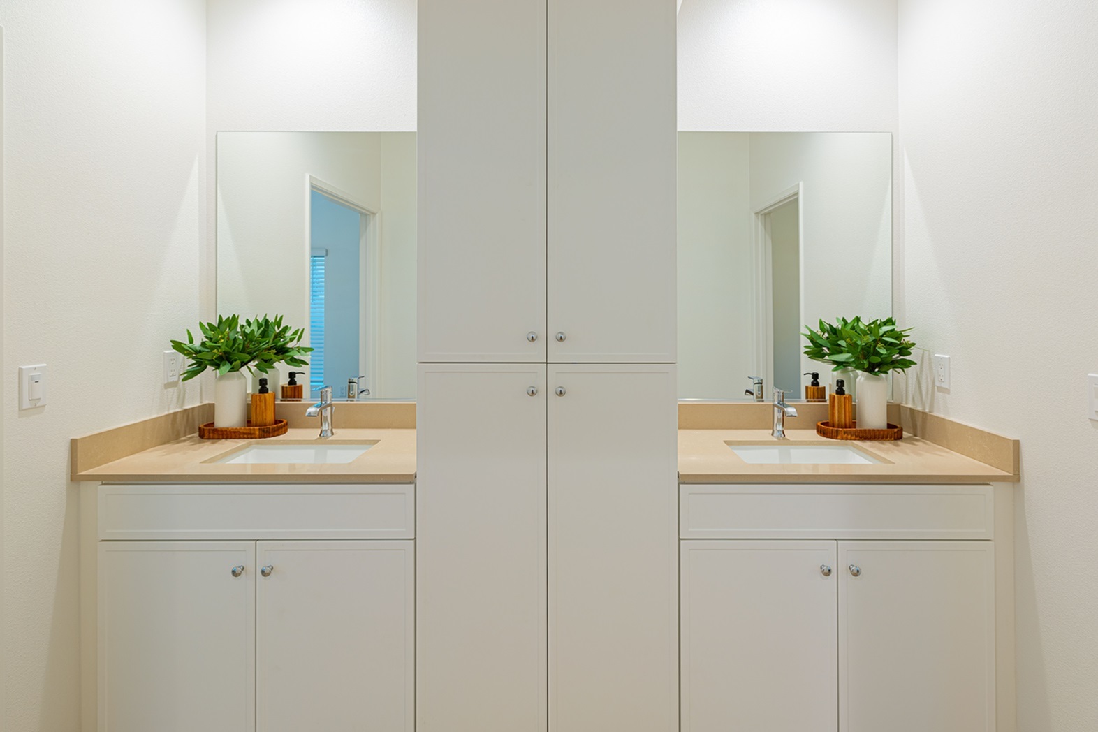 Elegant double vanity bathroom featuring shaker style white cabinetry, modern fixtures, and decorative greenery for a refreshing touch.
