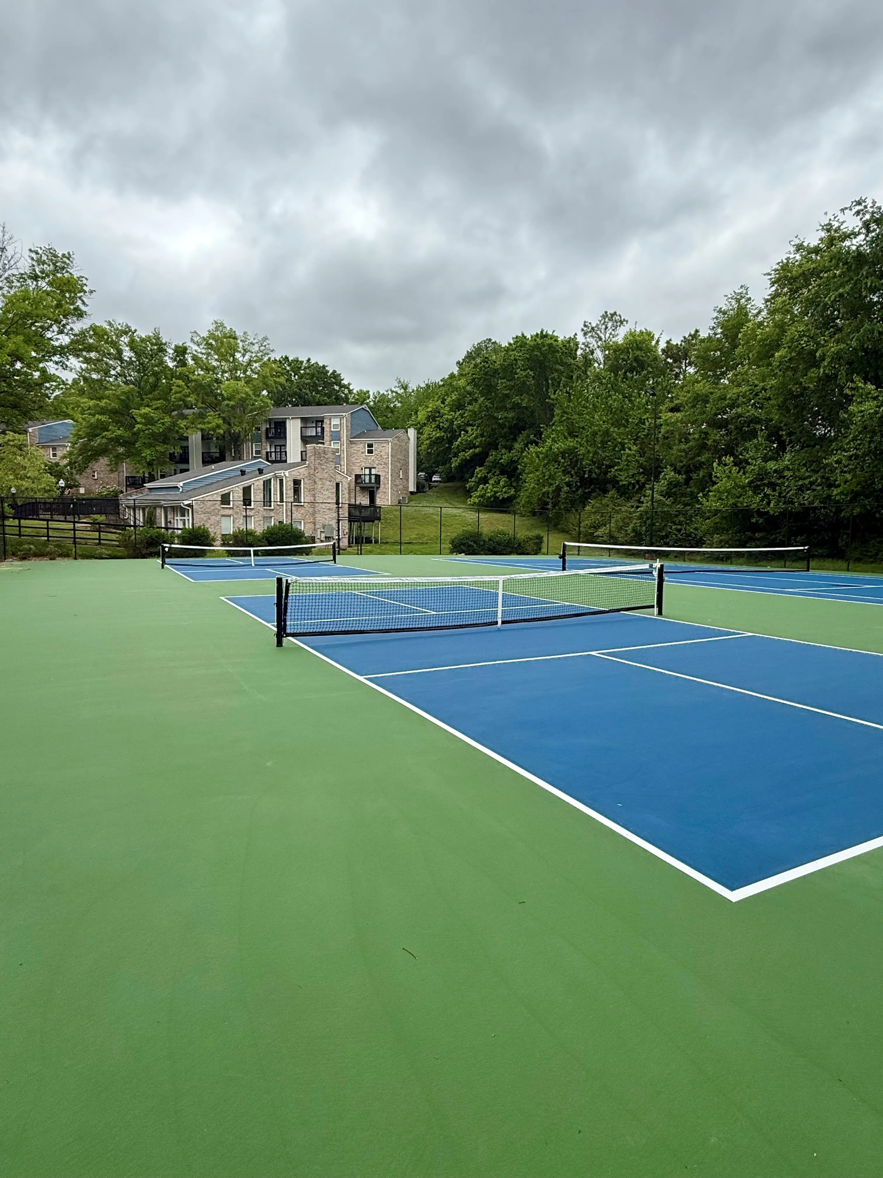 Modern apartment complex with tennis courts and lush green surroundings, perfect for active lifestyle seekers.