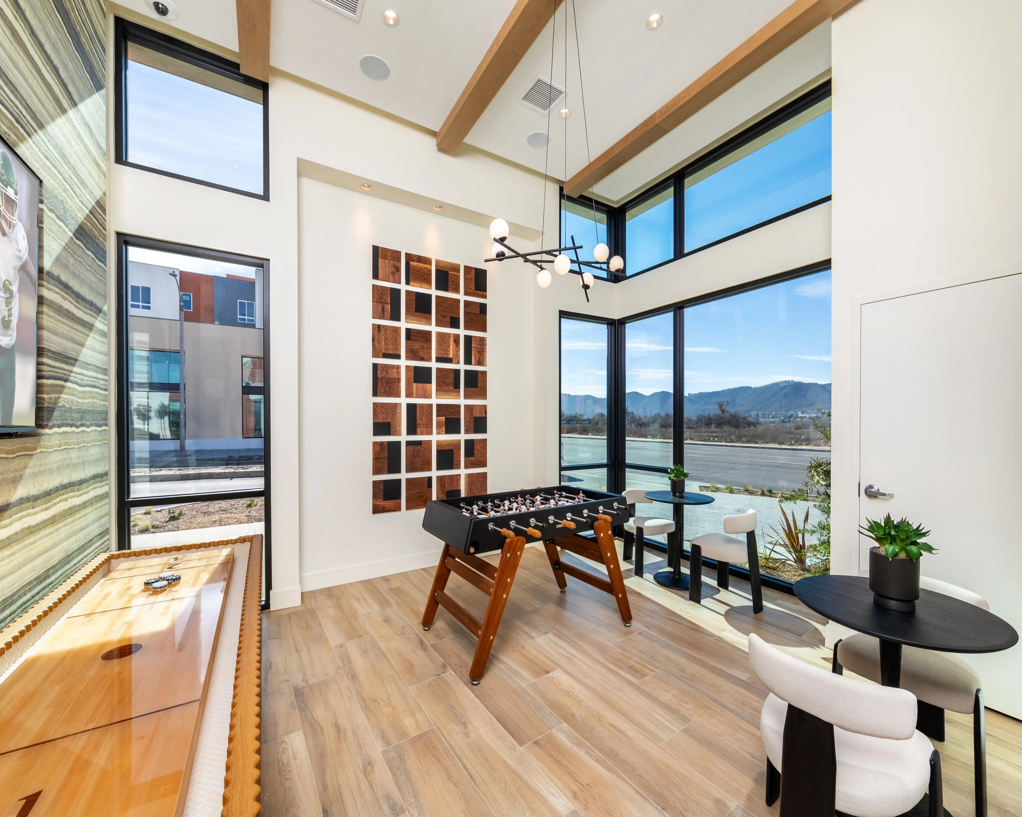 Bright and modern game room with foosball table, sleek decor, and large windows offering scenic views.