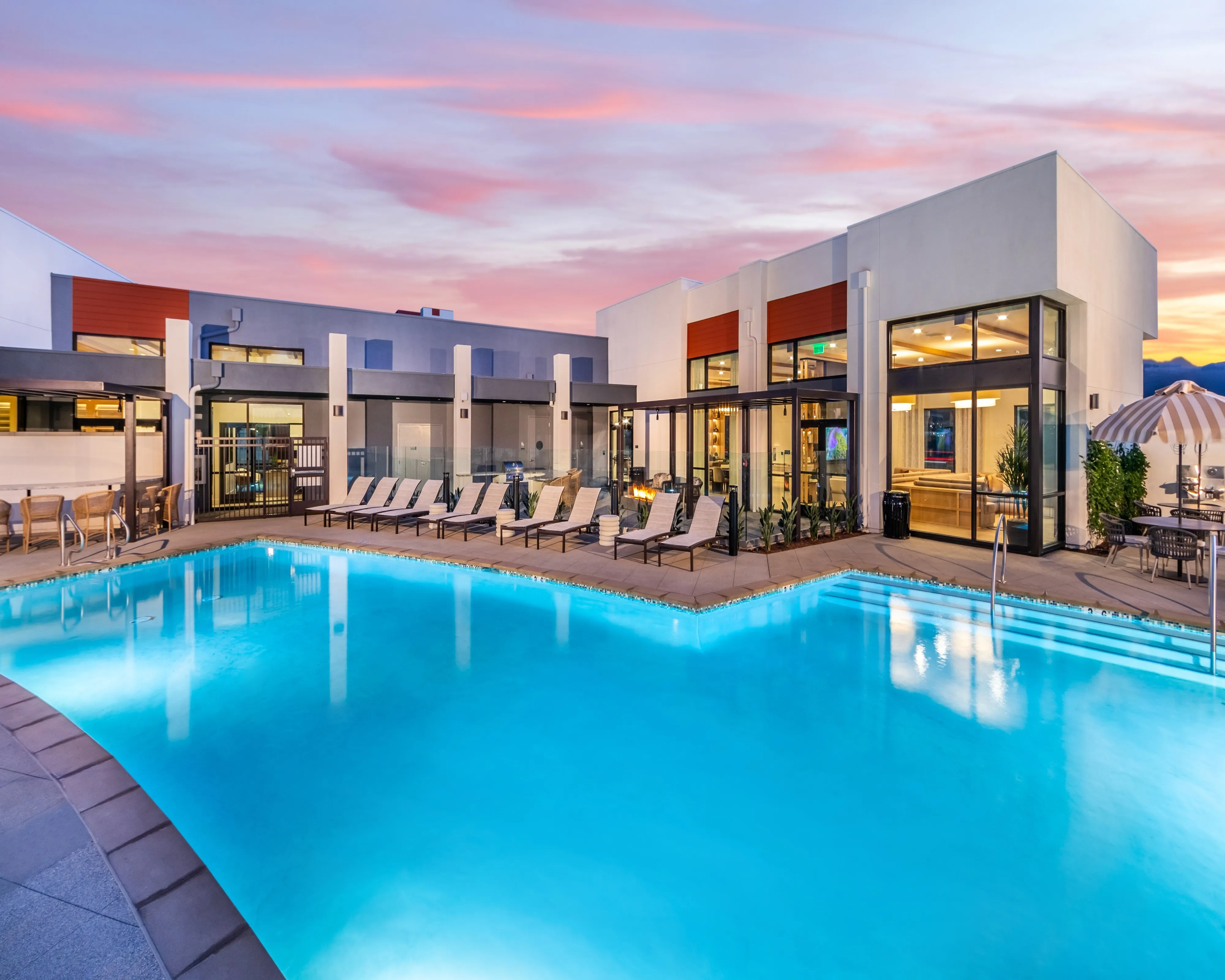 Luxurious apartment community featuring a stunning pool surrounded by stylish lounge chairs.