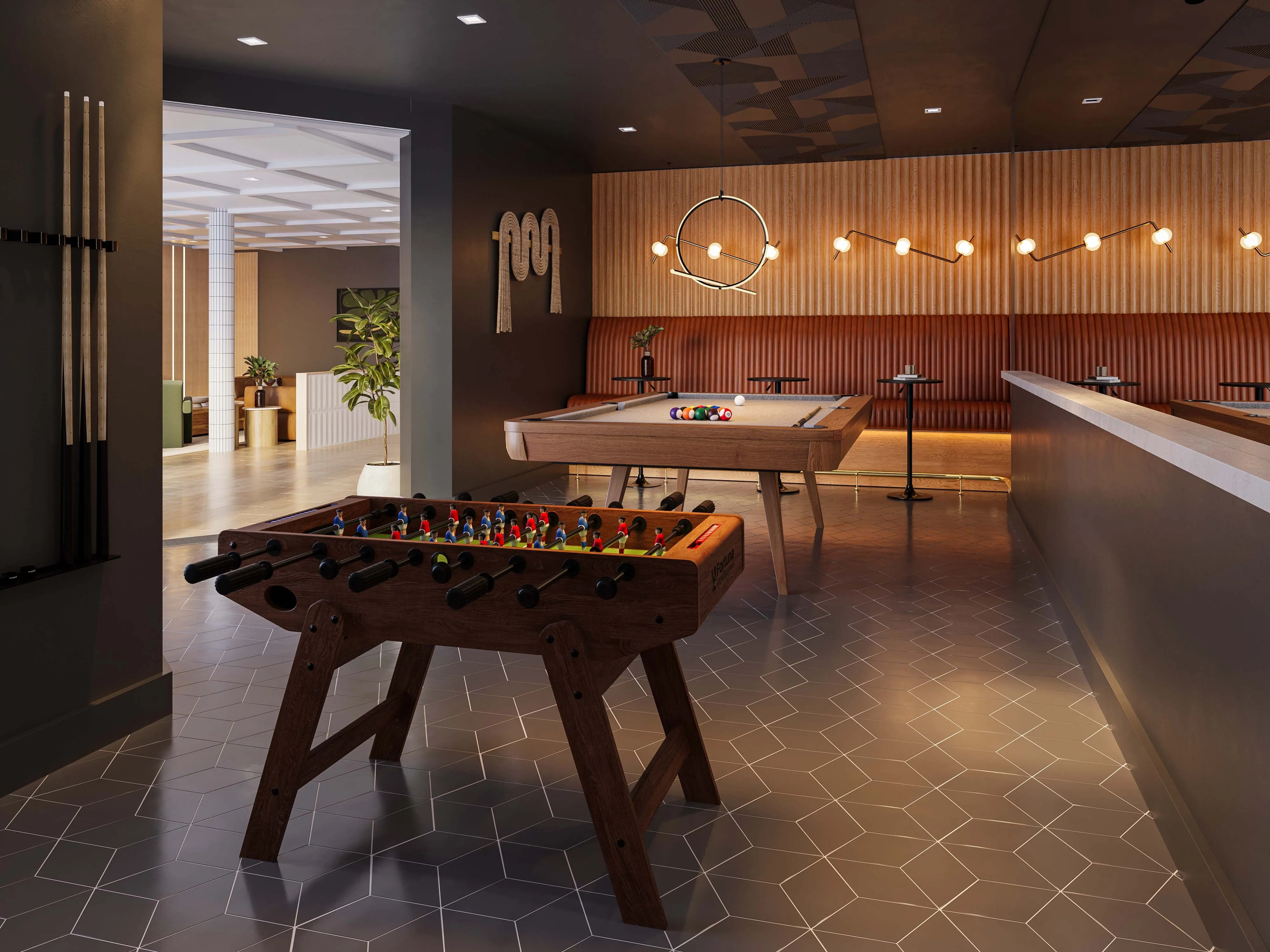 Game room featuring a stylish billiards table and foosball setup under ambient lighting, with cozy seating area and geometric tile flooring.