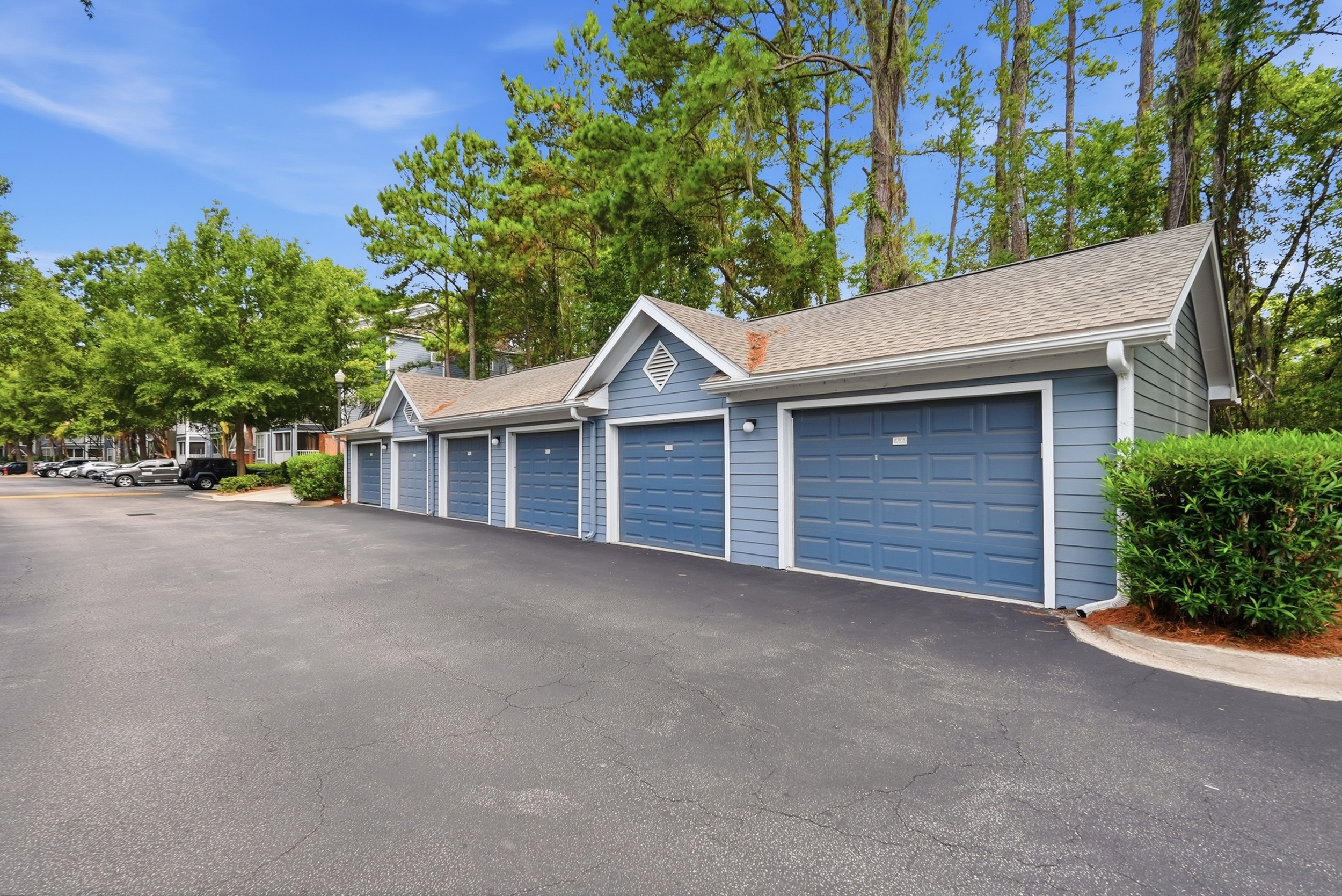 Charming apartment complex with well-maintained blue garages and lush greenery, creating a welcoming and serene environment.