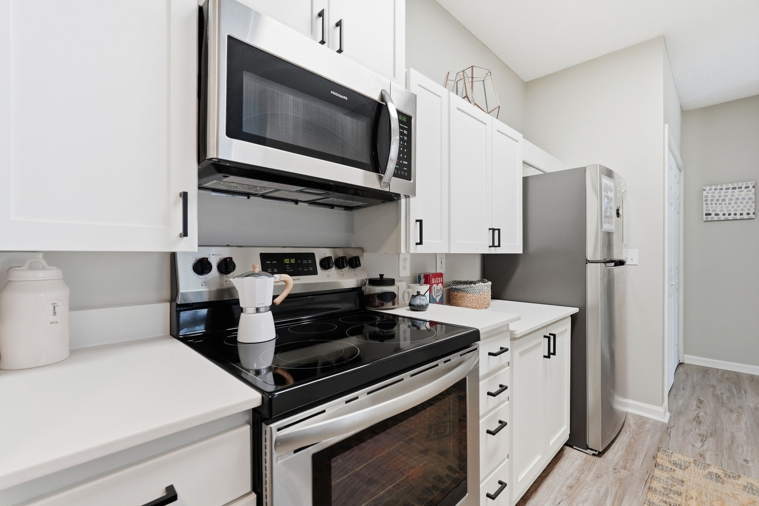Modern kitchen featuring sleek stainless steel appliances, elegant white cabinetry, and stylish hardwood floors.