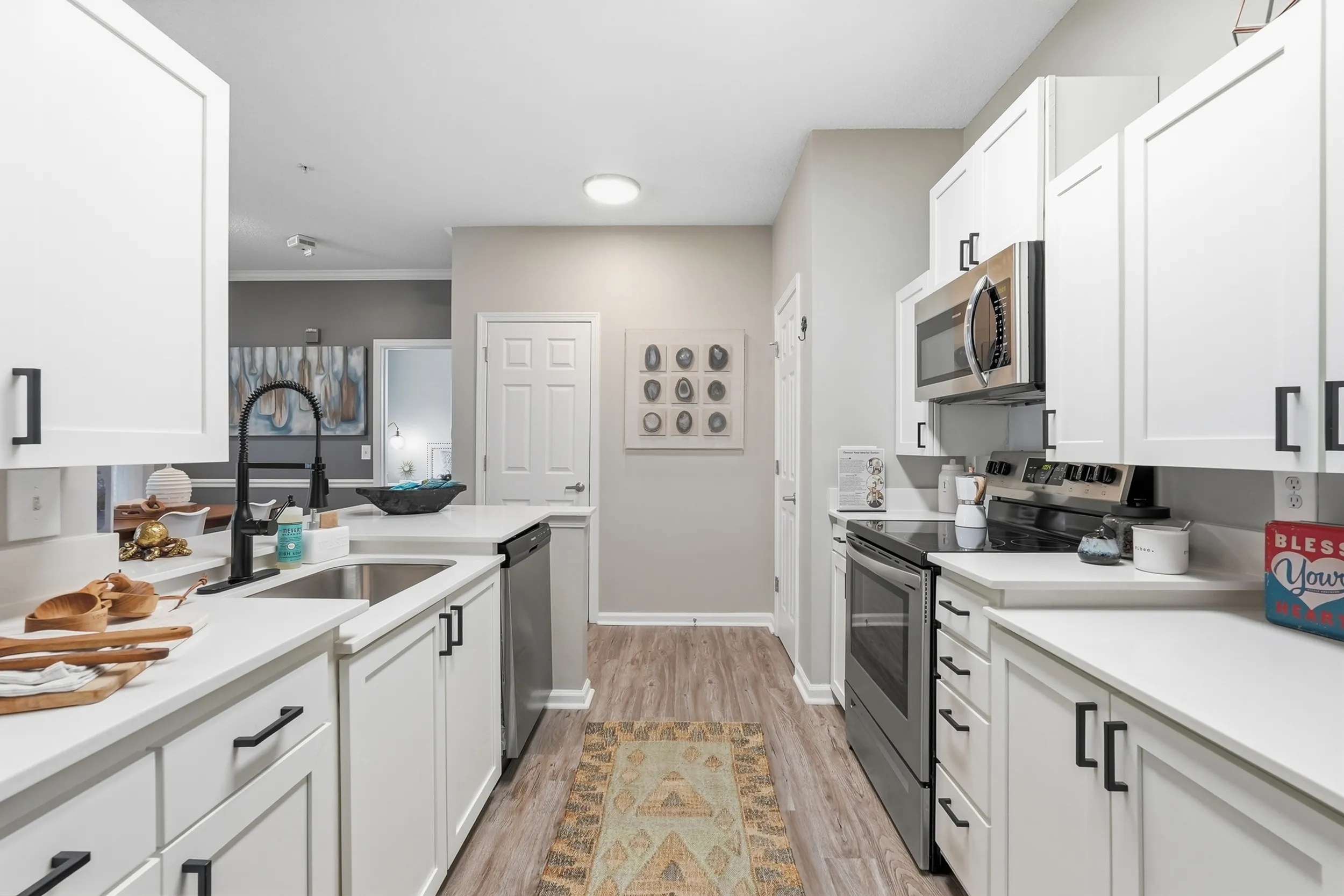 Modern kitchen with sleek white cabinetry, stainless steel appliances, and elegant hardwood flooring, perfect for culinary enthusiasts.