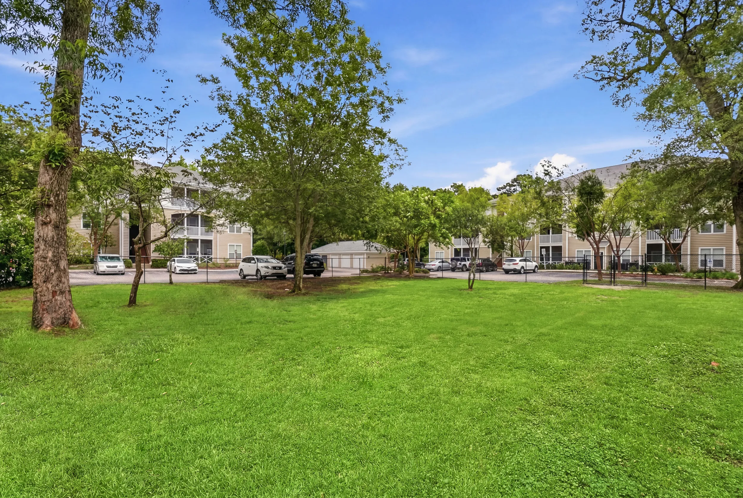 Beautiful apartment complex surrounded by lush green lawns and mature trees, creating a serene and inviting atmosphere.