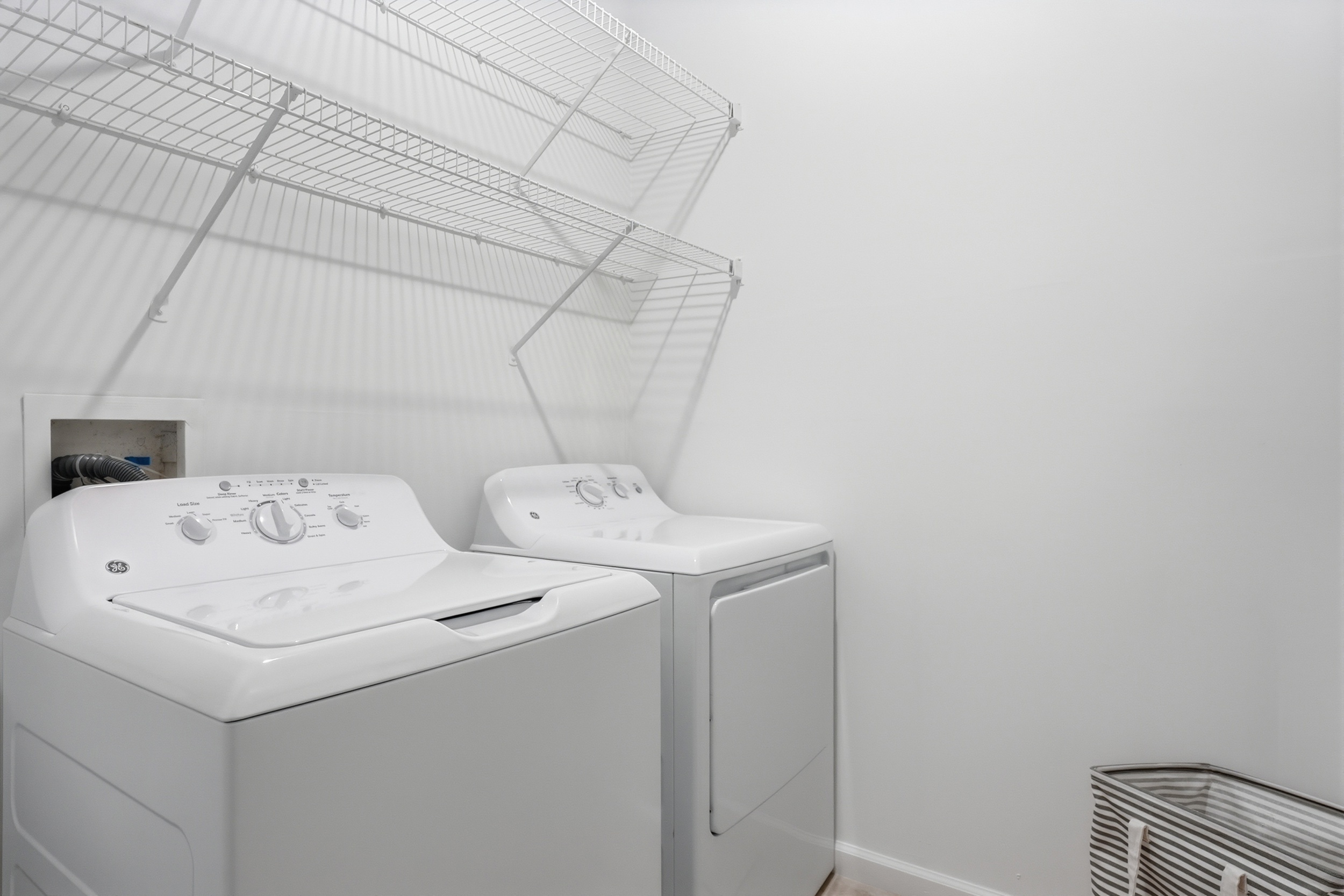 Chic and functional laundry room featuring modern washer and dryer with ample shelving for storage.