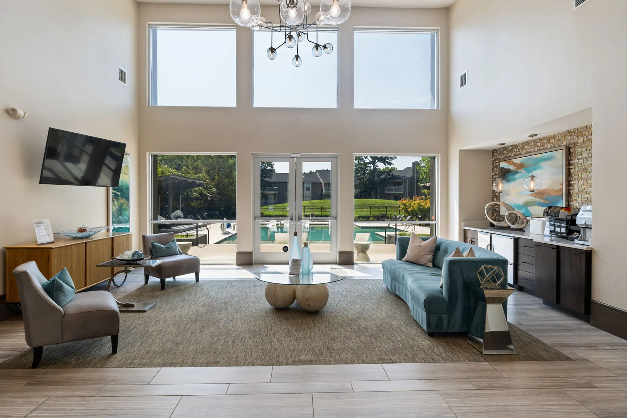 Bright and inviting lounge area with stylish furniture, high ceilings, and large windows overlooking a scenic pool view.