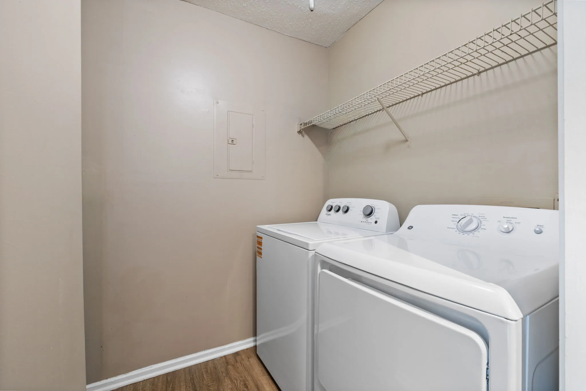 Modern laundry room equipped with state-of-the-art washer and dryer, featuring ample shelving and elegant neutral tones.