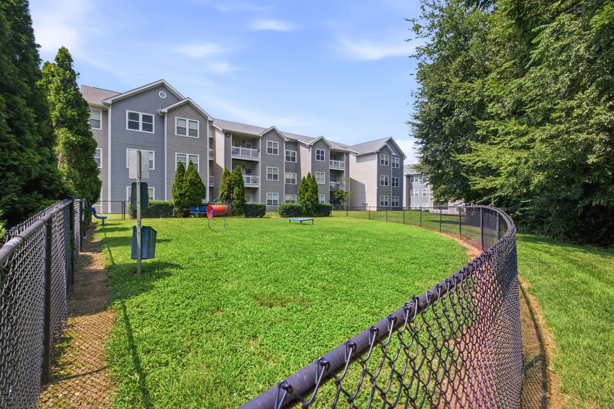 Charming apartment complex with lush green lawn, playground, and modern architectural design.