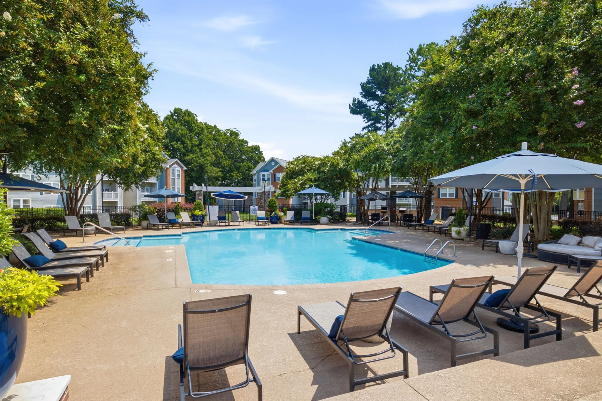 Inviting outdoor pool area with cozy lounge chairs and lush greenery, perfect for relaxation and leisure.