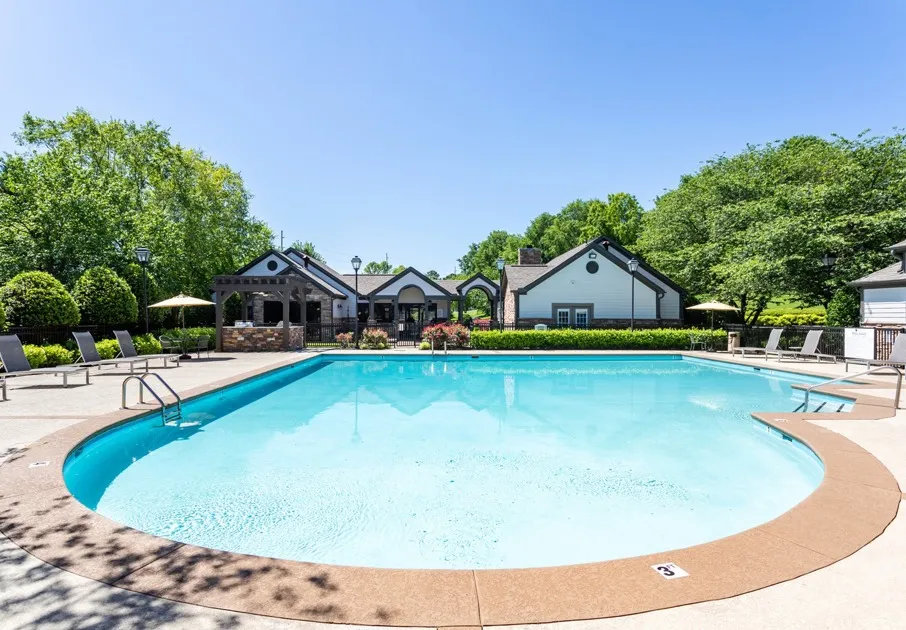 The pool area at our apartments for rent in Antioch, TN, featuring beach chairs, umbrellas, and a clubhouse.