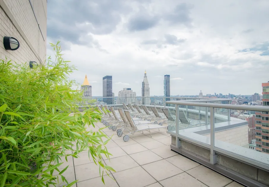 Rooftop lounge at our apartments for rent in Flatiron, featuring beach chairs and a view of the New York skyscrapers.