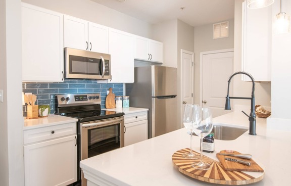 Model kitchen at our apartments for rent in Mooresville, featuring stainless steel appliances and white countertops.