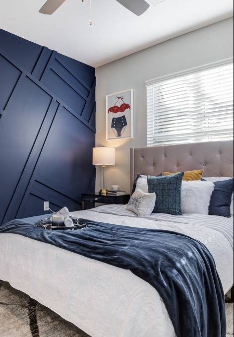 Model bedroom at our apartments for rent in Mooresville, NC, featuring a blue wall and window with blinds.