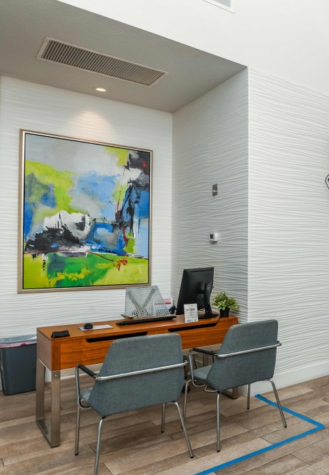 Leasing office at Avana City Park apartments in Clearwater, FL, featuring wood grain flooring and a desk with two chairs.