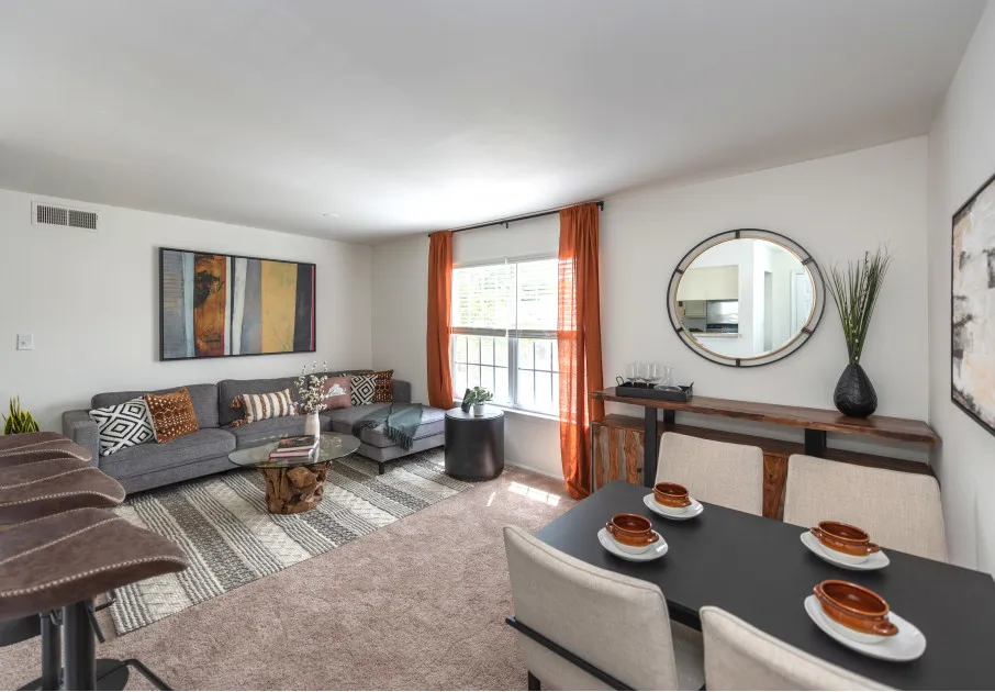 Model living room at our apartments for rent in Leesburg, VA, featuring a dining room table, couch, and rustic decor.