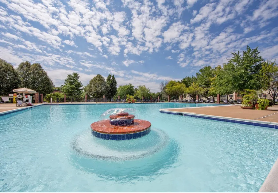 The pool at our apartments for rent in Leesburg, VA, featuring beach chairs, umbrellas, and a fountain.