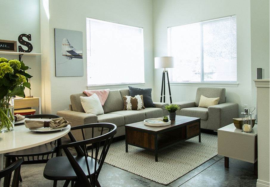 Model living room at our apartments for rent in Kenmore, WA, featuring large windows and a dining room table