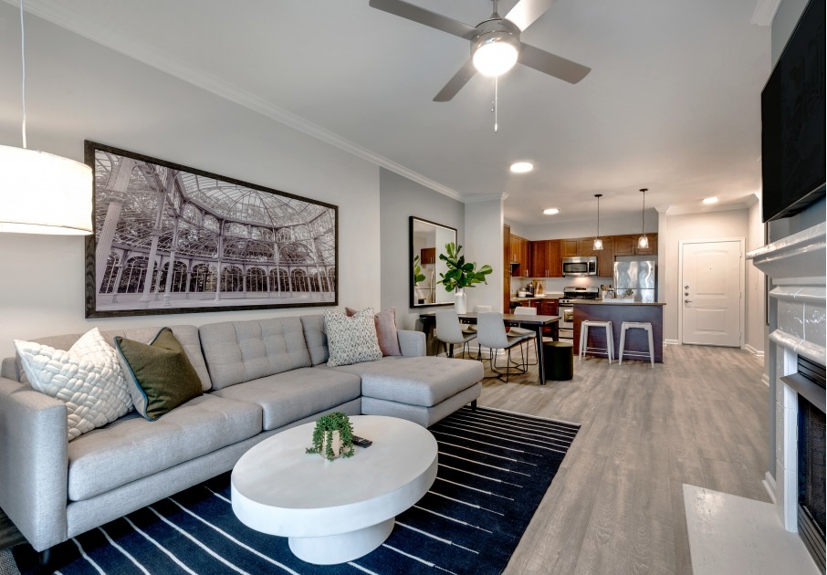 Model living room at our apartments for rent in Herndon, VA, featuring wood grain floor paneling and a long grey couch.