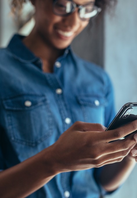 Young professional woman smiling while looking at her cellphone in our Delray Beach apartments for rent.