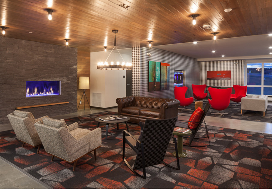 Model living room at our apartments for rent in Kenmore, WA, featuring a modern fireplace and chandelier.