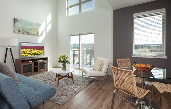 Model living room at our apartments for rent in Kenmore, WA, featuring wood grain floors and a dining room table.