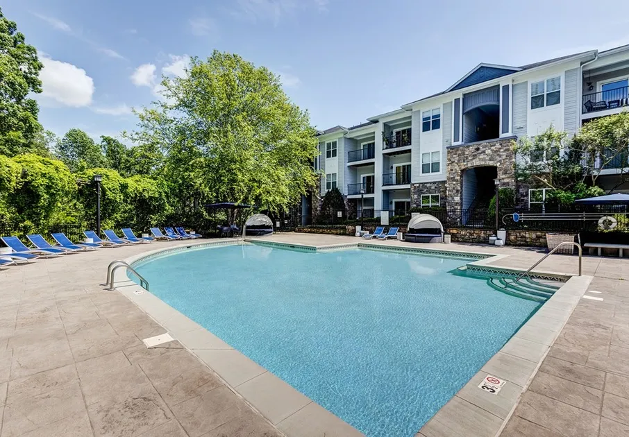 The pool area at our apartments for rent in Mooresville, NC, featuring beach chairs and a view of the apartments.