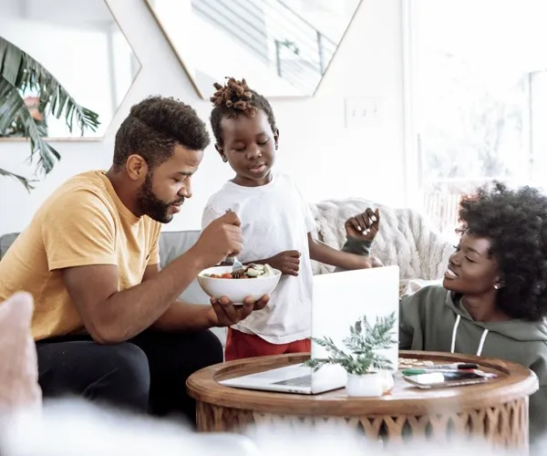 A family eating together in the living room of an apartment at Marlowe Live Oak Apartments in St Cloud, FL.