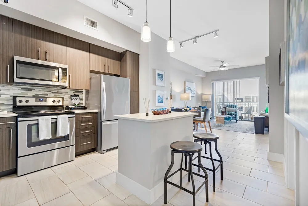 Model kitchen at our apartments for rent in Boca Raton, FL, featuring an island with seating, an oven and a refrigerator.