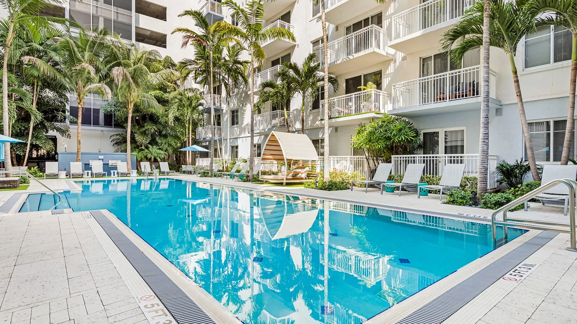 Outdoor swimming pool at our apartments for rent in Boca Raton, FL, featuring lounge chairs and shaded seating.