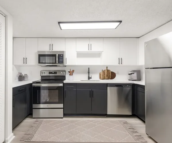 Model kitchen at Avana Palm Beach Gardens in Palm Beach Gardens, FL, featuring wood grain flooring and white countertops.