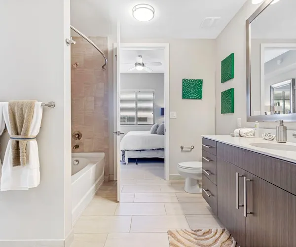 Model bathroom off a bedroom at our apartments for rent in Boca Raton, FL, featuring a shower and vanity mirror.