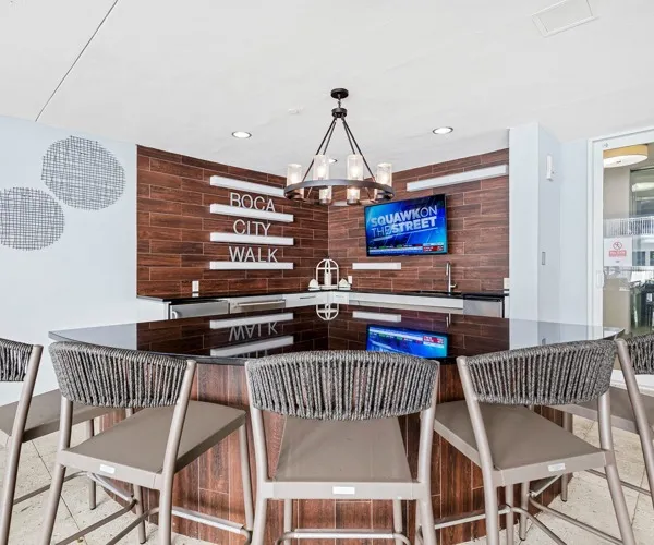 Model kitchen and dining space at our apartments for rent in Boca Raton, FL, featuring an island with seating, and a chandelier.