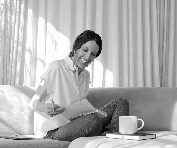 Person sitting on a couch with a notebook on their lap.