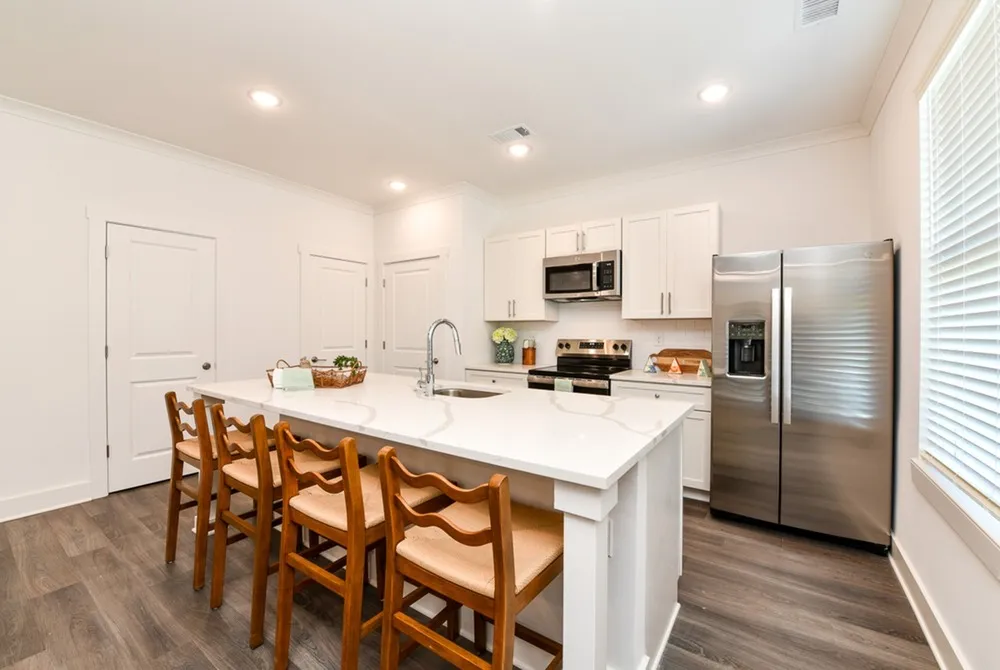 Model kitchen at our townhomes for rent in Fairburn, GA, featuring a kitchen island with seating, and a refrigerator.