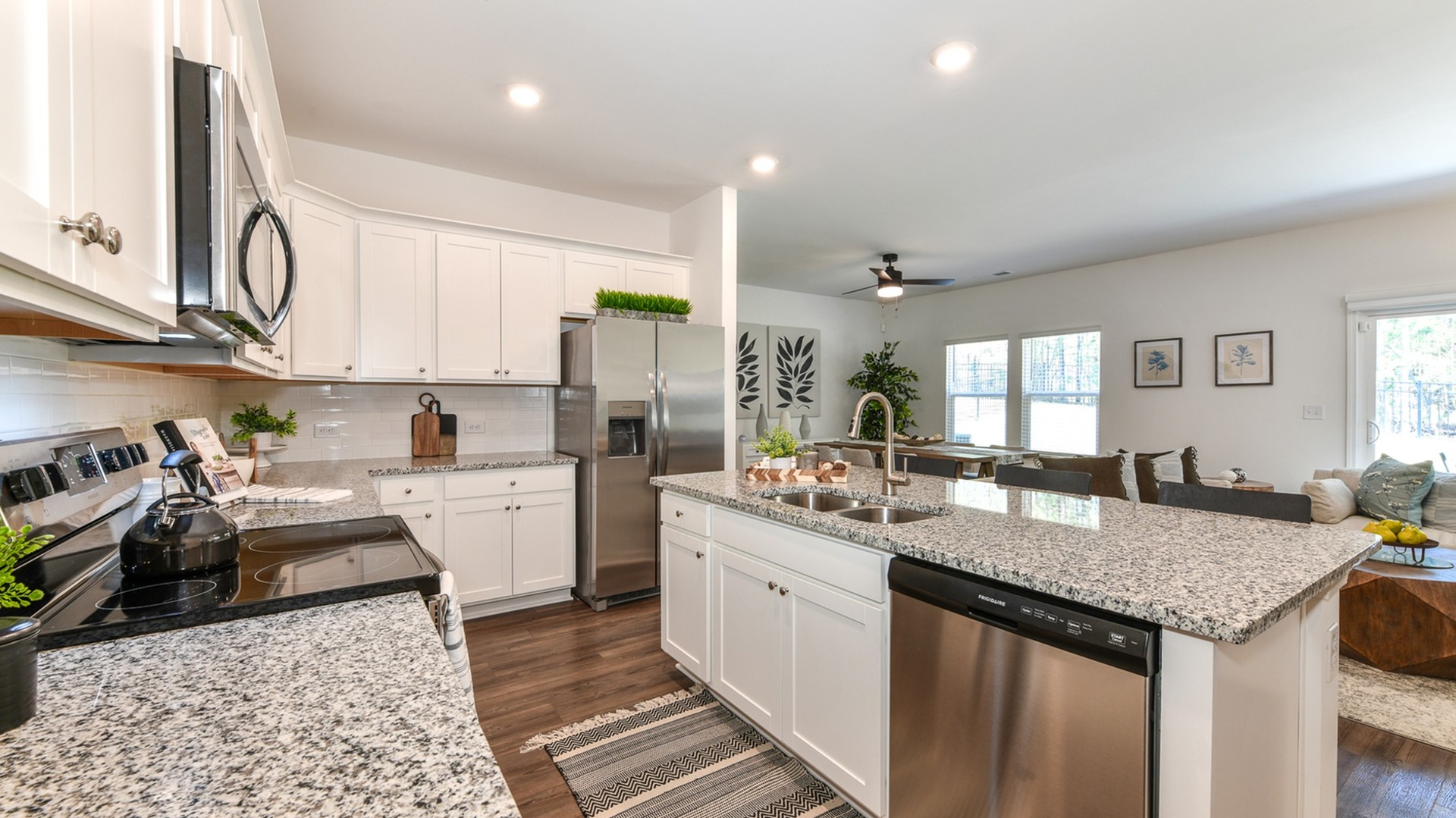 Model kitchen at Summerwell Deerhaven houses in Union City, GA, featuring wood grain floor paneling and granite counters.