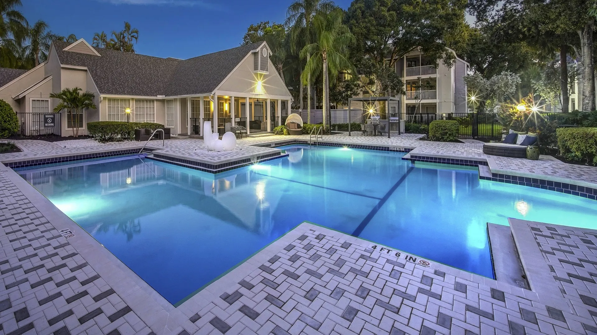 Outdoor swimming pool at Avana Coral Springs apartments, featuring modern lounge seating and palm trees.