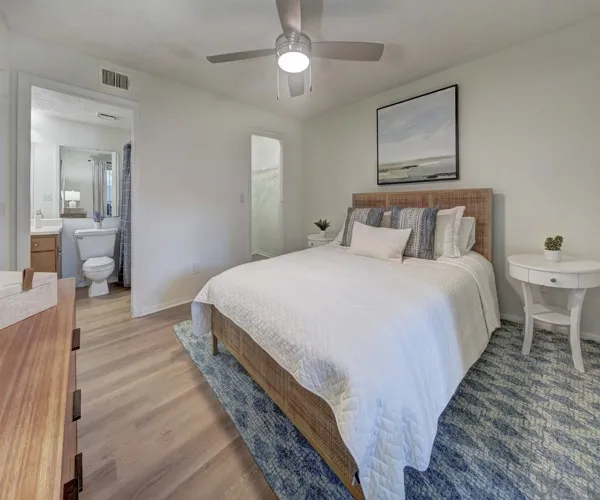 Model bedroom at Avana Coral Springs apartments, featuring wood grain flooring and a private bathroom.