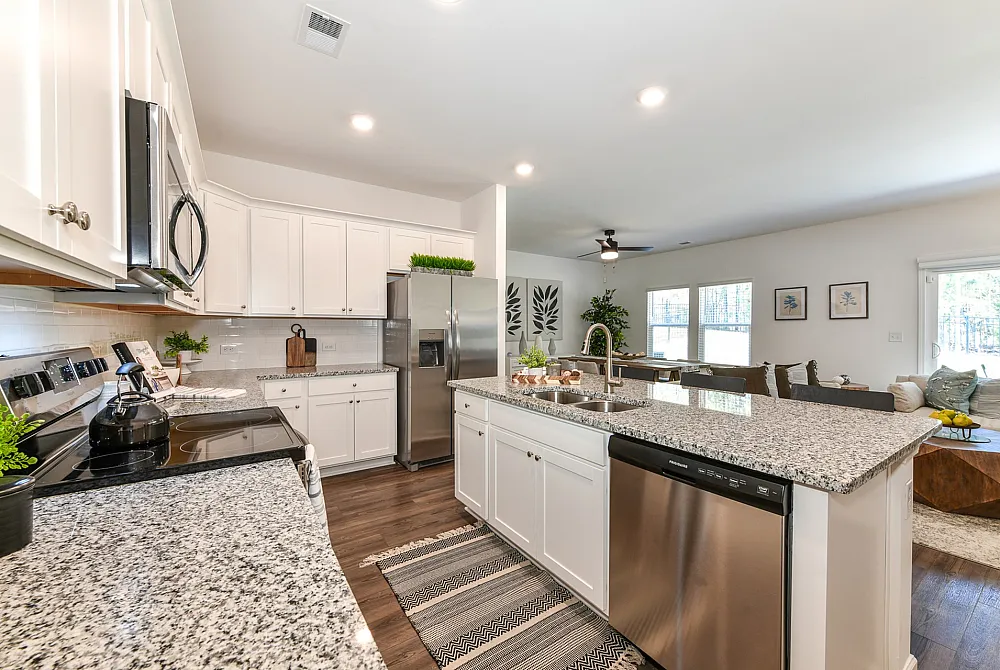 Model kitchen at Summerwell Deerhaven houses in Union City, GA, featuring wood grain flooring and white cabinetry.