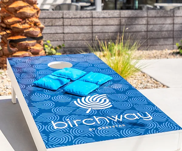 Vibrant outdoor lounging area featuring a stylish cornhole game with bright blue bean bags on a modern patio, perfect for relaxation and entertainment.