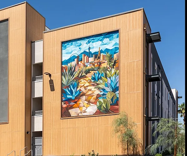 Modern apartment building with a vibrant mural under a clear blue sky, showcasing stylish urban living.