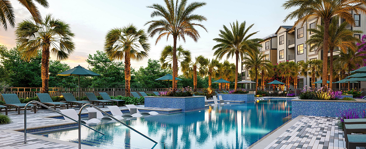Luxurious apartment complex featuring a stunning pool surrounded by lush palm trees and elegant loungers, offering serene relaxation in a tropical paradise setting.